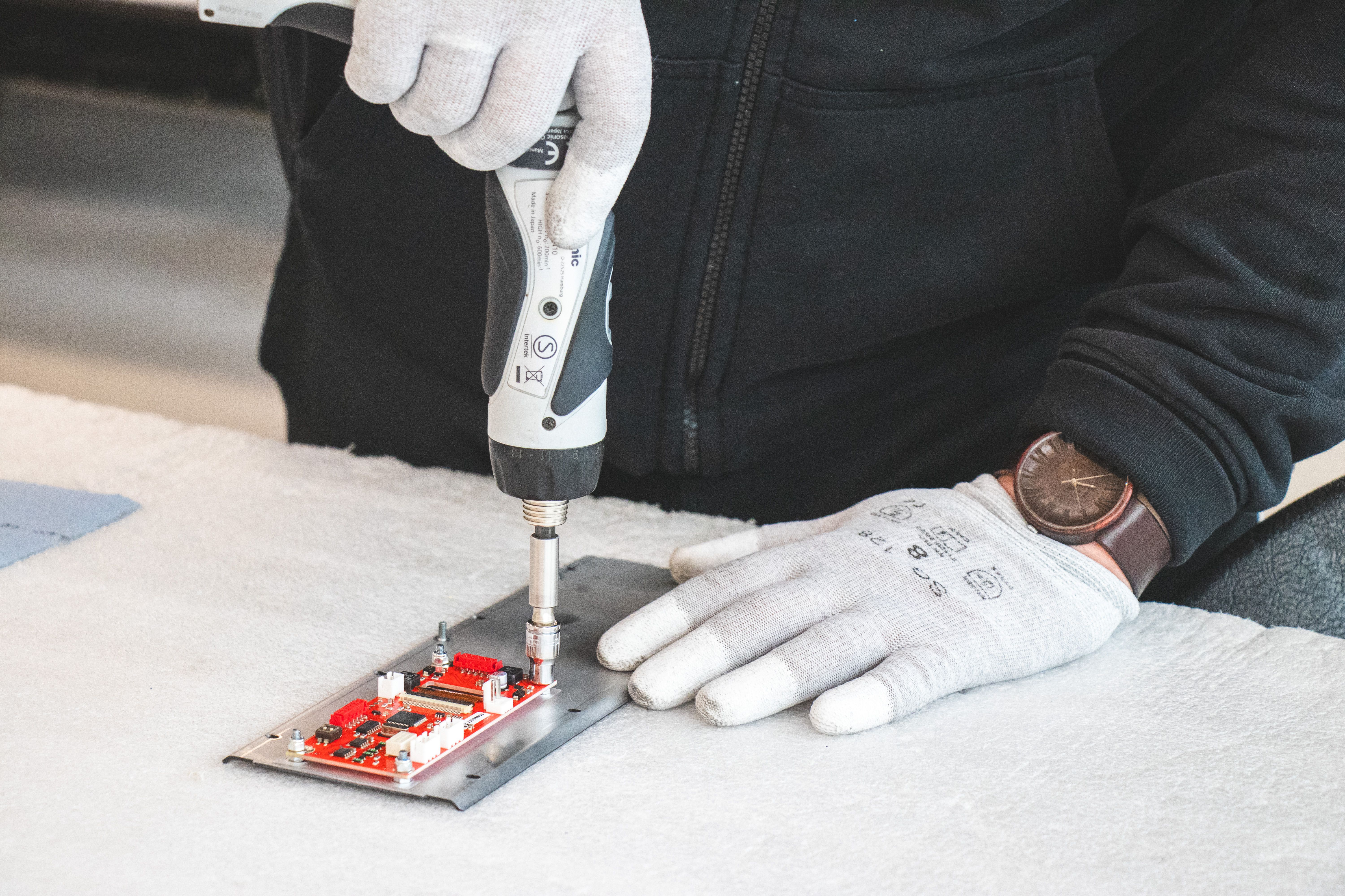 Two hands, using a tool to assemble a prototype.